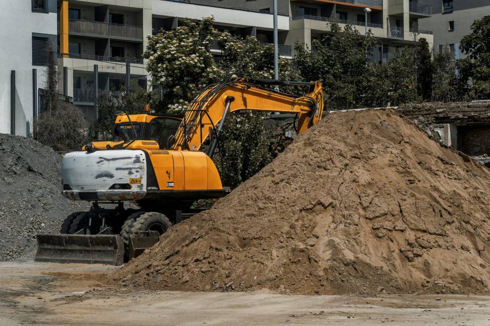 Yellow excavator moving dirt on construction site.