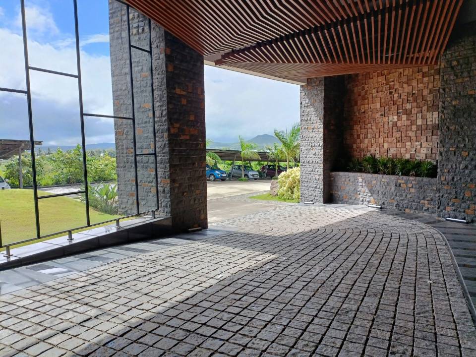 Modern cobblestone driveway with wooden ceiling structure.