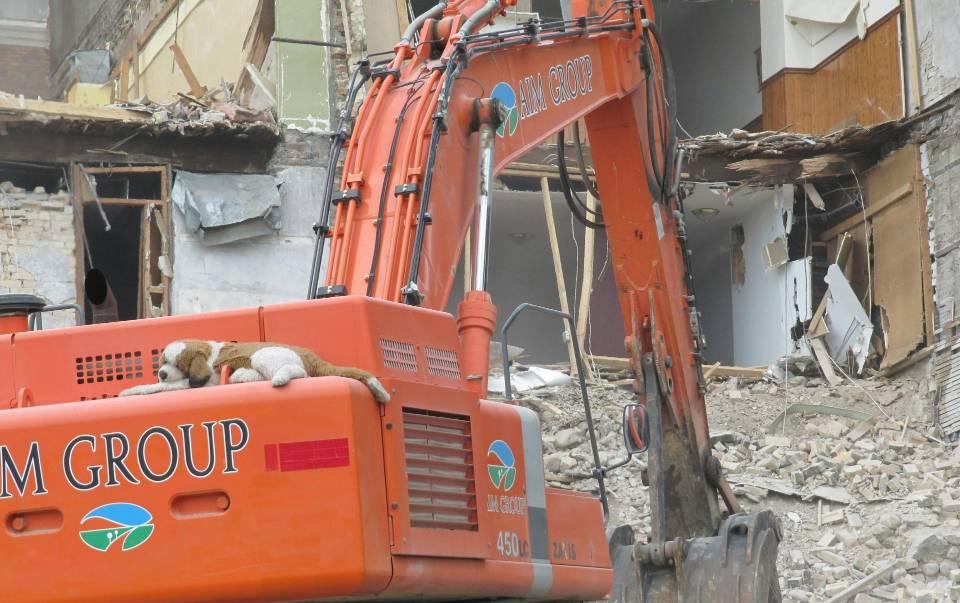 Excavator demolishing a building with stuffed toys.