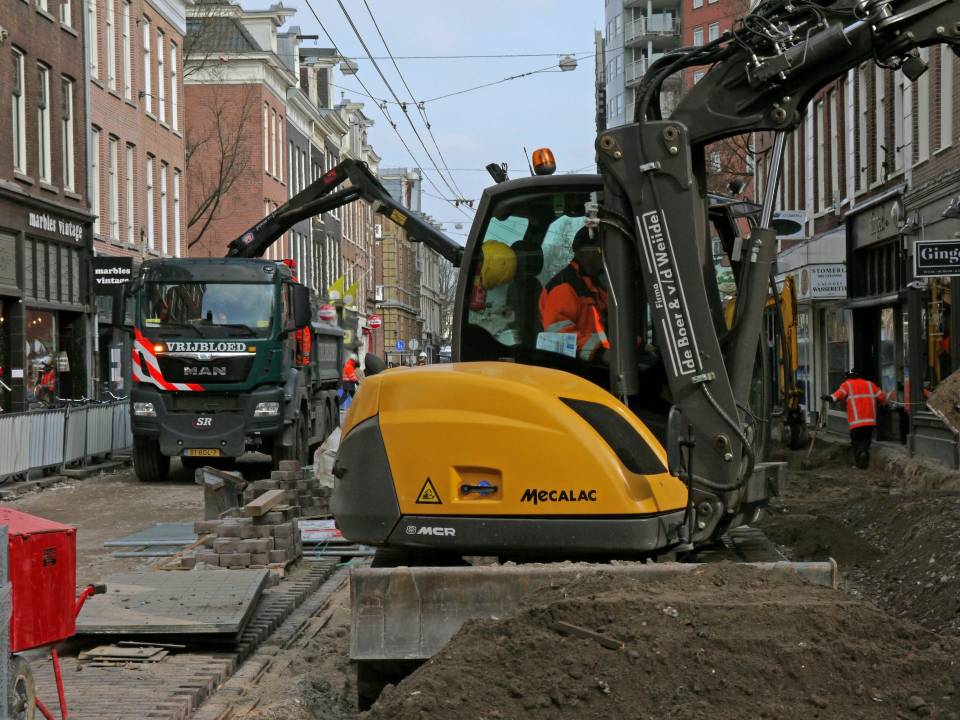 Yellow excavator working on city road construction.