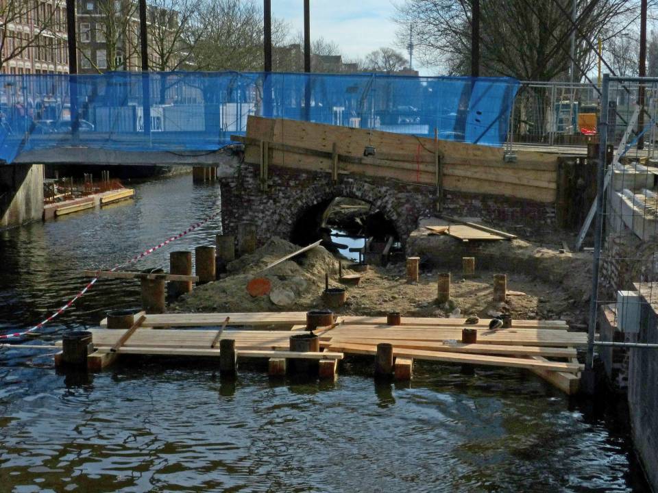 Construction site with wooden planks over canal.